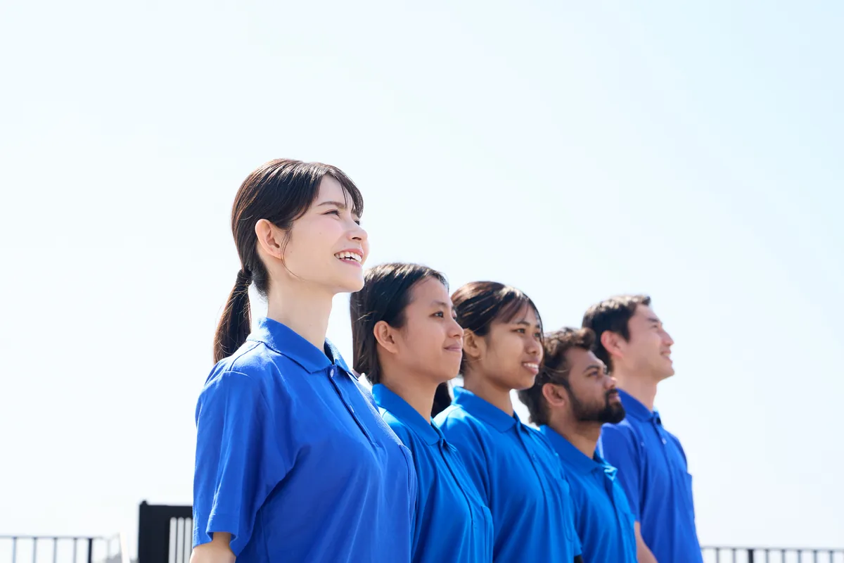 介護施設で働く外国人スタッフと日本人職員が笑顔で並ぶ様子