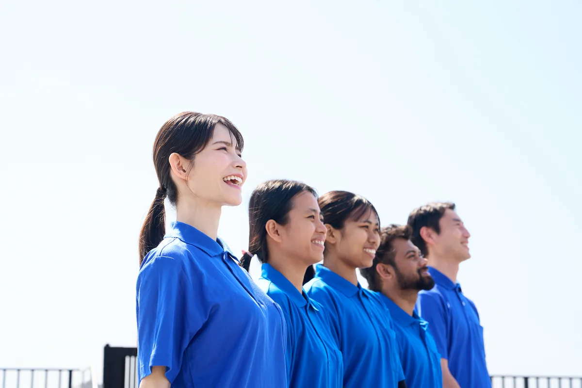介護施設で外国人スタッフと日本人職員が笑顔で並ぶ様子